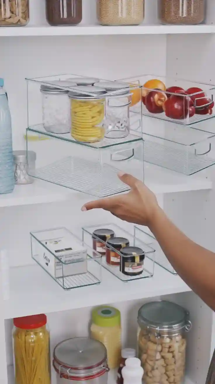 A beautifully organized pantry with food stored in clear stackable bins, a key kitchen organization idea.